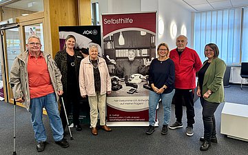 Das Foto zeigt (v.l.) Karl Huss (Selbsthilfegruppe Diabetes), AOK-Kundencenterleiterin Susanne Engelhardt, Doris Niemann (Selbsthilfegruppe Recover), Sigrun Ruck (Leitung des Selbsthilfenetzwerkes Neckar-Odenwald), Walter Gellner (Selbsthilfegruppe Morbus Crohn & Colitis ulcerosa) und Kristina Haase (Sozialer Dienst der AOK) vor einem der neun Rollups.
