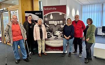 Das Foto zeigt (v.l.) Karl Huss (Selbsthilfegruppe Diabetes), AOK-Kundencenterleiterin Susanne Engelhardt, Doris Niemann (Selbsthilfegruppe Recover), Sigrun Ruck (Leitung des Selbsthilfenetzwerkes Neckar-Odenwald), Walter Gellner (Selbsthilfegruppe Morbus Crohn & Colitis ulcerosa) und Kristina Haase (Sozialer Dienst der AOK) vor einem der neun Rollups.