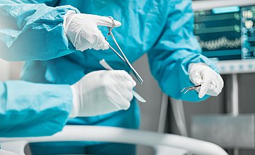 AOK-Klinikvergleich in Schleswig-Holstein Ein Operateur hält während der OP verschiedenes OP-Besteck in Händen, um damit etwas in der OP auszuführen.