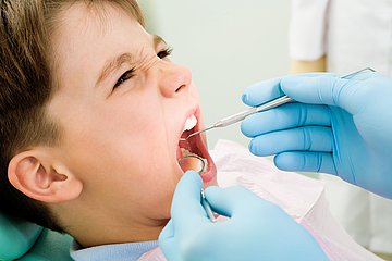 Tag der Zahngesundheit in Westfalen-Lippe Das Foto zeigt einen kleinen Jungen als Nahaufnahme, bei dem eine Ärztin die Zähne kontrolliert.