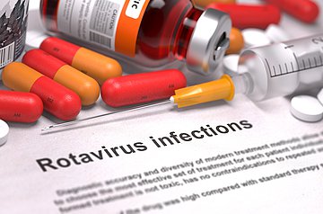 Rotavirus-Fälle in Westfalen-Lippe Auf einer Textseite mit Überschrift 'Rotavirus infections' liegen farbige Kapseln, weiße Tabletten, eine Serumfläschchen sowie eine aufgezogene Spritze.