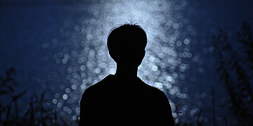 Foto: Die Silhouette eines Mannes vor einem dunklen, nachtblauen Himmel.