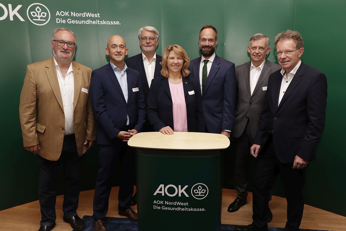 Auf dem Foto sind AOK-Verwaltungsrat Lutz Schäffer, KGSH-Geschäftsführer Patrick Reimund, Henrik Herrmann (Präsident Ärztekammer Schleswig-Holstein), Landes-Gesundheitsministerin Kerstin von der Decken, AOK-Chef Tom Ackermann, AOK-Verwaltungsrat Johannes Heß sowie Norbert Roeder (Roeder und Partner) zu sehen.