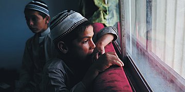 Pakistan Foto von zwei traditionell gekleideten pakistanischen Jungen auf einem roten Sofa