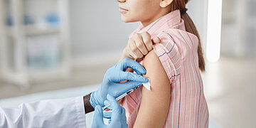 Ein M&auml;dchen wird vom Arzt geimpft.