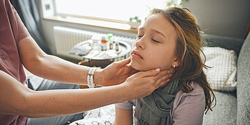 Eine Frau tatstet einem jungen M&auml;dchen die Lymphknoten am Hals ab.