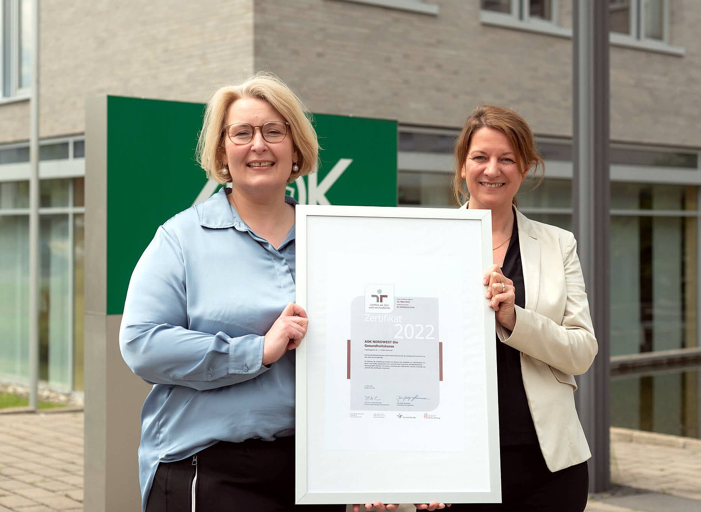 AOK-Personalvorständin Iris Kröner (rechts) und Gleichstellungsbeauftragte Claudia Fuest halten das Zertifikat in die Kamera.