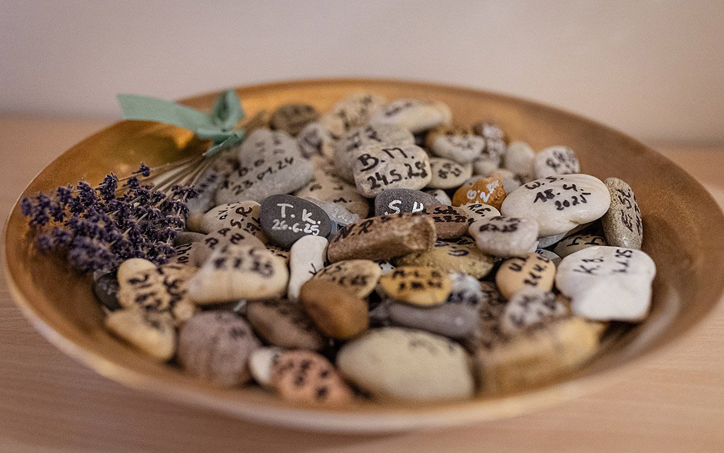 Foto: Viele kleine Steine auf einem Teller – auf jedem Stein steht das Sterbedatum eines Verstorbenen.