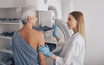 Patientin bei einem Mammographie-Screening, unterst&uuml;tzt von einer Medizinerin.