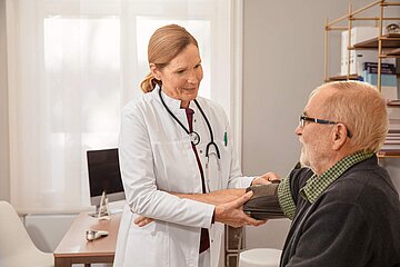 Eine &Auml;rztin misst bei einem Patienten den Blutdruck.