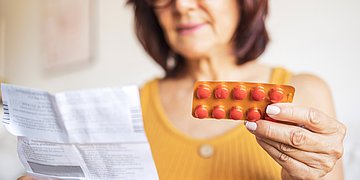 Medikamente und Sonnenlicht Eine Frau hält einen Blister mit Tabletten in der Hand und liest die Packungsbeilage.