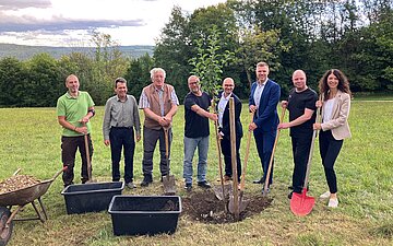 Eine Gruppe von Menschen pflanzt einen Apfelbaum