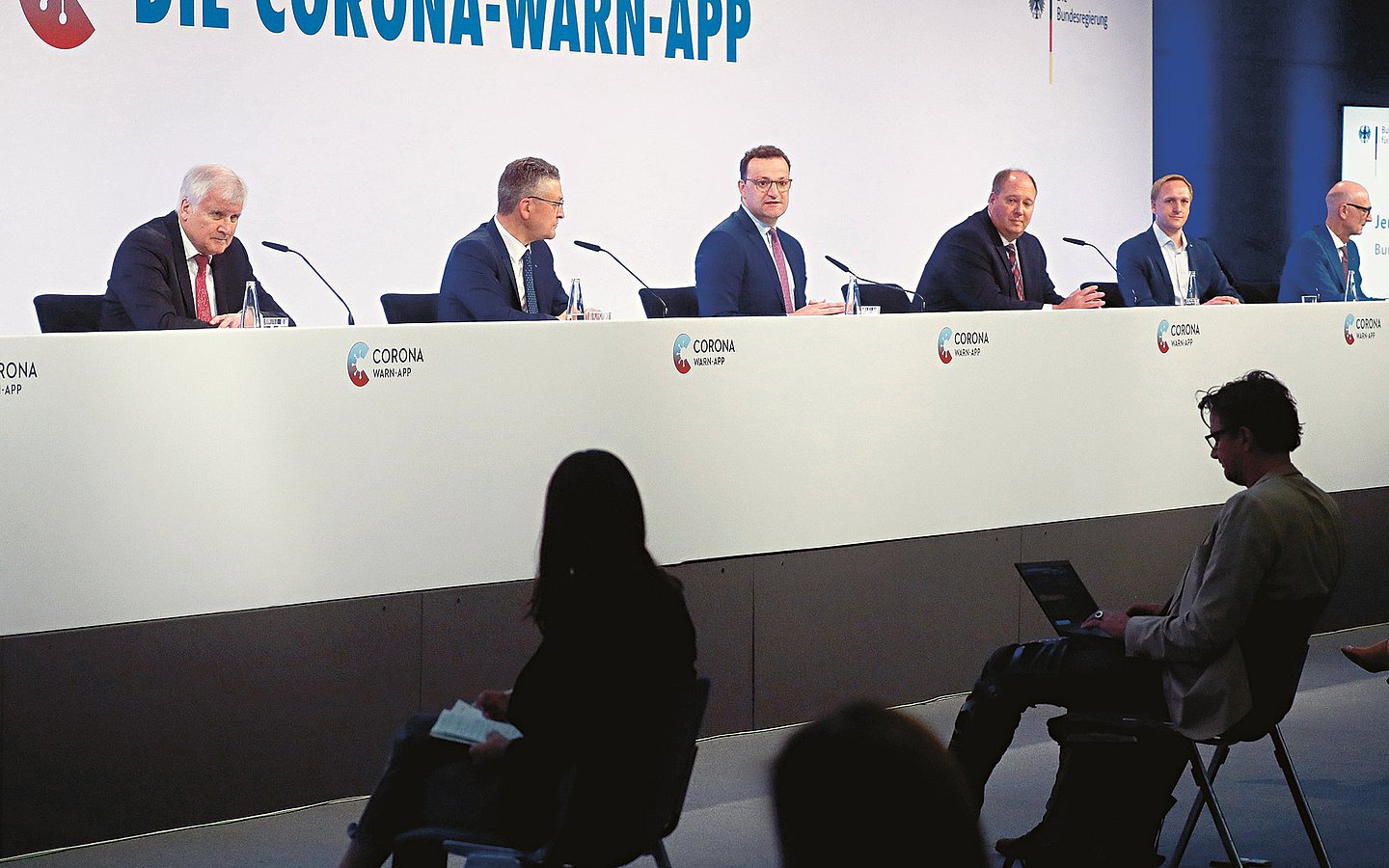 Foto: Konferenz zur Vorstellung der Corona-Warn-App mit Menschen auf Podium