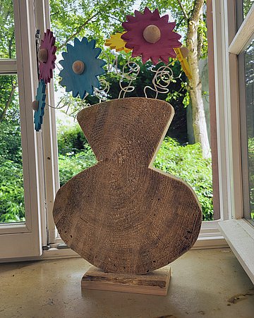 Foto: Dekorative Holzvase mit bunten Blumen.