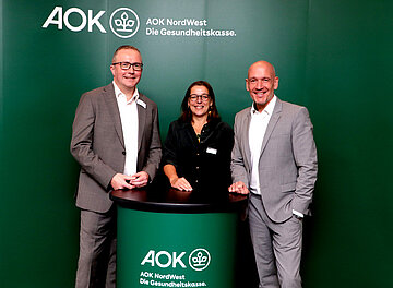 Auf dem Foto sind Dr. Christoph Vauth (stellvertretender AOK-Vorstandsvorsitzender), Prof. Dr. Dorothee Lebeda (Katholische Hochschule NRW) und Maik Vonau (Fachbereichsleiter Pflege bei der AOK) zu sehen.
