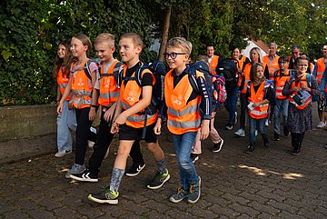 Grundschüler bei Einweihung des AOK Walking Bus Grundschulkinder mit Warnwesten auf dem Schulweg.