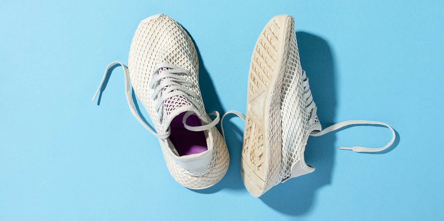 Foto: Turnschuhe, einer steht, einer liegt, auf einem blauen Hintergrund.