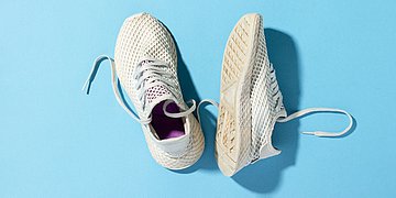 Foto: Turnschuhe, einer steht, einer liegt, auf einem blauen Hintergrund.