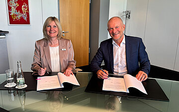 Nicole Dietl, Mitglied des Vorstandes der Sparkasse Offenburg/Ortenau, und Wolfgang Schweizer, Gesch&auml;ftsf&uuml;hrer der AOK Mittlerer Oberrhein, sitzen bei der Vertragsunterzeichnung in Achern an einem gemeinsamen Tisch.
