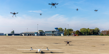 Ein Flugplatz, &uuml;ber dem verschiedene Drohnen in der Luft schweben.