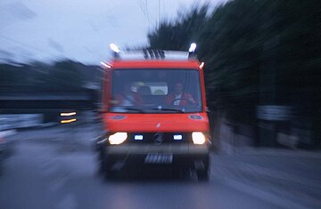 Ein Rettungswagen mit Blaulicht f&auml;hrt schnell &uuml;ber eine Stra&szlig;e.