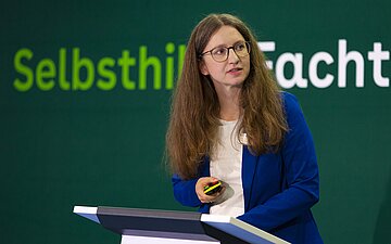 Peggy Heinz steht hinter einem Rednerpult auf einer B&uuml;hne