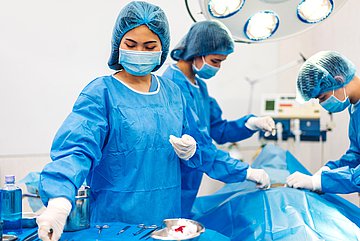 Die Kliniken in NRW erhalten mehr Geld für die Versorgung der Patienten Ein Team aus Ärzten und OP-Schwestern operiert einen Patienten im OP- Im Vordergrund greift eine der OP-Schwestern nach einem Instrument für den operierenden Arzt.