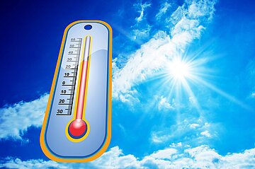 Ein Thermometer vor einem sommerlich blauen Himmel, an dem die Sonne scheint.
