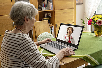 Eine &auml;ltere Dame ist bei einer Videosprechstunde zu Hause am Laptop.