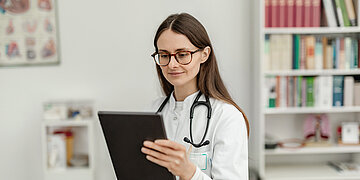 Eine &Auml;rztin gibt Daten in ein Tablet ein.