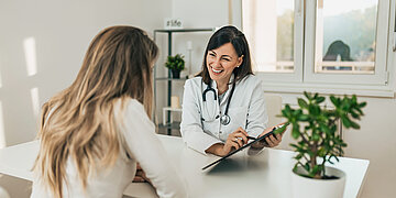 Eine &Auml;rztin und eine Patientin befinden sich in einem freundlichen Gespr&auml;ch