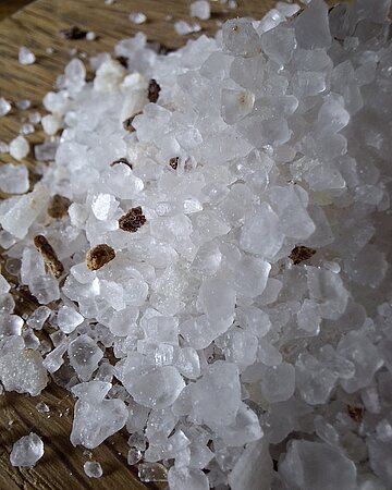 Ein H&auml;ufchen mit Salzkristallen auf einer Tischplatte.