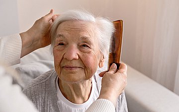 Pflege durch Angehörige Eine alte Frau wird gekämmt.