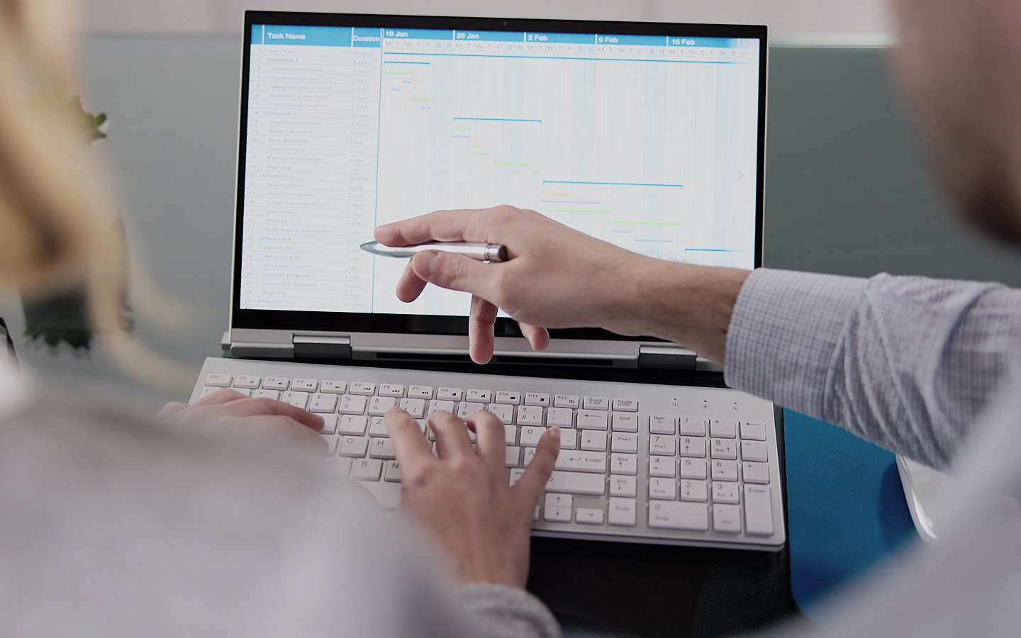 Versichertendaten Foto: Zwei medizinische Mitarbeitende sitzen vor einem Notebook. Eine Person zeigt mit einem Kuli auf Daten auf dem Bildschirm.