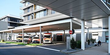 Foto: Blick auf mehrere Rettungswagen in einer Einfahrt eines Krankenhausses n&auml;he der Notaufnahme