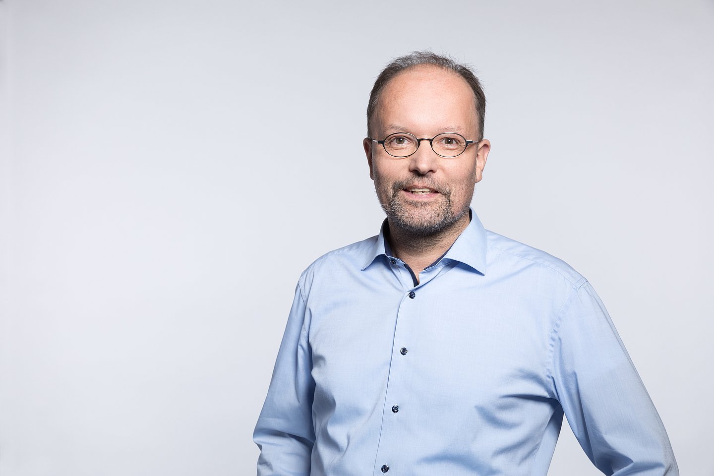 Porträtfoto zeigt Kopf und Rumpf, Ralf Metger trägt eine ovale Brille und ein hellblaues Hemd.