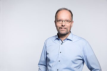 Portr&auml;tfoto zeigt Kopf und Rumpf, Ralf Metger tr&auml;gt eine ovale Brille und ein hellblaues Hemd.