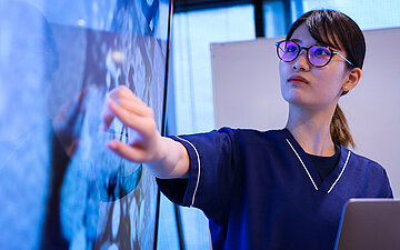 Foto: Eine Gesundheitsfachkraft oder &Auml;rztin zeigt auf ein R&ouml;ntgenbild.