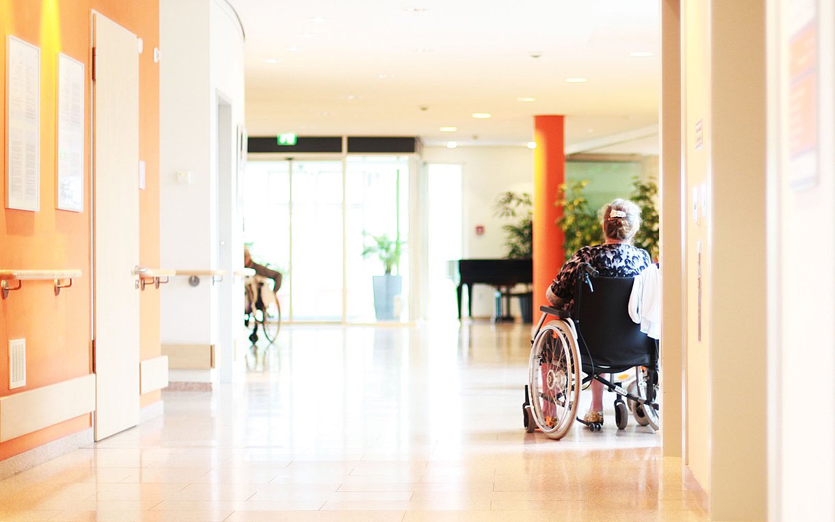 Foto einer alten Dame im Rollstuhl in einem Pflegeheim