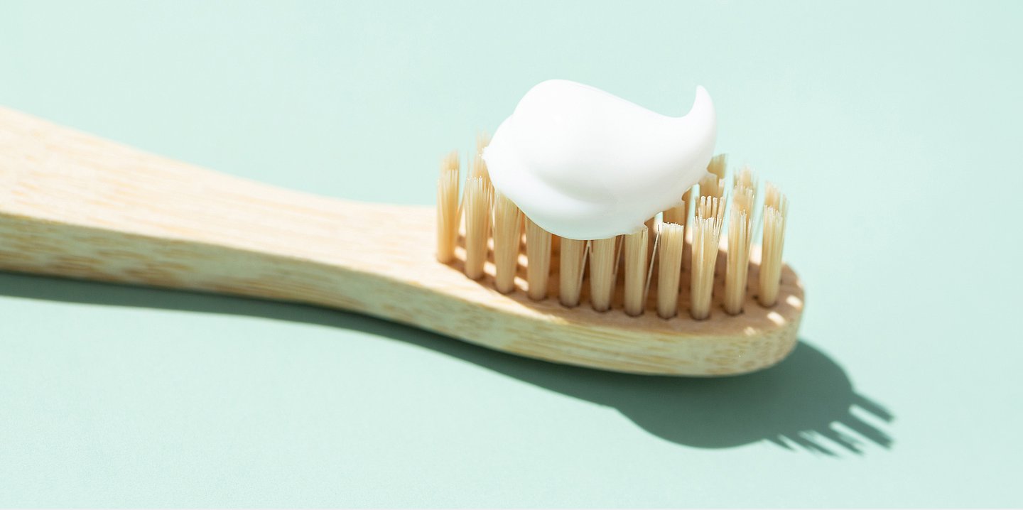Foto: Auf einer Holzzahnbürste ist ein Klecks Zahnpasta.