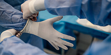 Im OP: ein Person bekommt einen Handschuh &uuml;bergestreift.