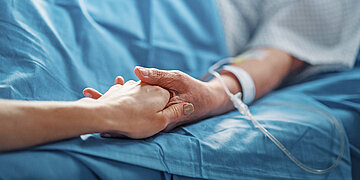 Foto von einer Hand, die eine andere Halt h&auml;lt, in der eine Infusionsnadel steckt