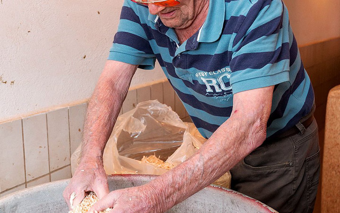 Foto: Ein Bewohner eines Pflegebauernhofs bereitet Einstreu im Stall vor.