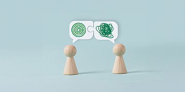 Gefühlsblindheit Zwei Spielfiguren stehen sich gegenüber und haben Sprechblasen mit unklaren Zeichen über den Köpfen.