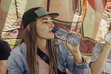 Eine junge Frau trinkt aus einer Wasserflasche