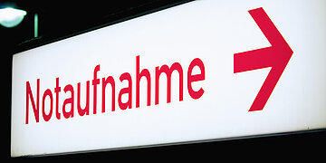 Foto: Wei&szlig;es Leuchtschild mit roter Schrift "Notaufnahme" und Pfeil nach rechts.