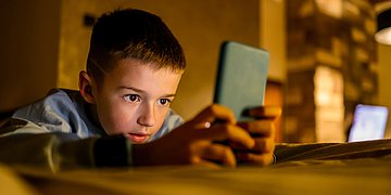 Ein Junge blickt konzentriert auf sein Smartphone.