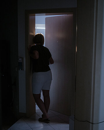 Foto: Lena Riepl schaut ins abgedunkelte Zimmer ihrer Tochter Elli, in dem nur ged&auml;mpftes lilafarbenes Licht brennt.