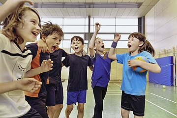 Schmuckfoto zeigt eine Gruppe junger Kinder lachend und jubelnd nach Sport und Bewegung