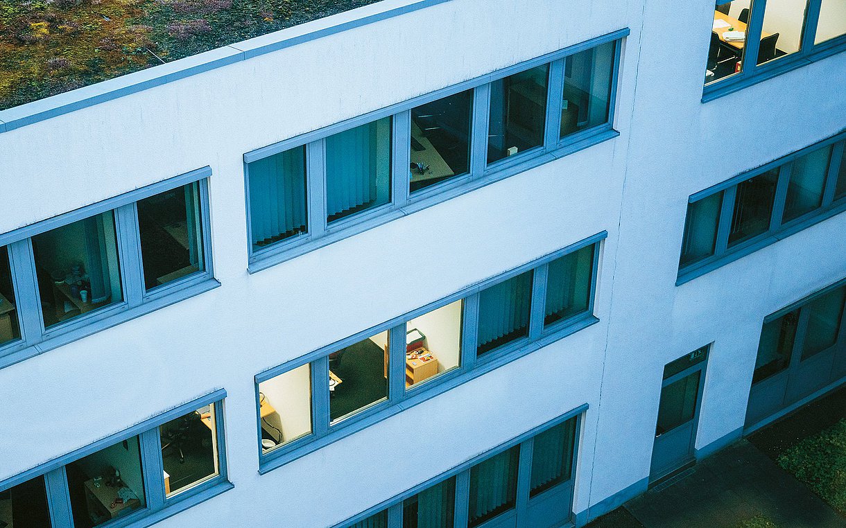 Aus der schrägen Vogelperspektive ist ein Bürogebäude mit Fensterfront zu sehen. 